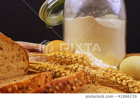Loafs of bread, slices of bread, wheat flour, eggs and ears of grain on wood background. Rustic and 41866239