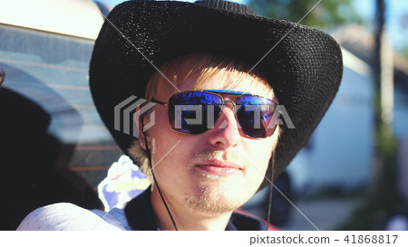 Handsome cowboy in hat and sunglasses traveling in a pickup truck in sunny day 41868817