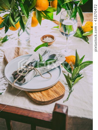 Table setting with white plate, cutlery, linen napkin and orange tree branch decoration on white Table setting with white plate, cutlery, linen napkin and orange tree branch decoration on white 41870472