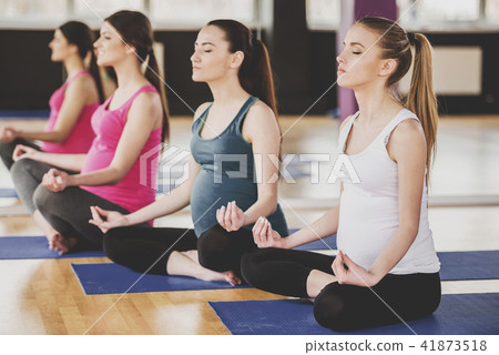 Group of Pregnant Women Meditating on Mats in Gym. 41873518