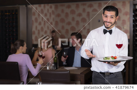 Young waiter with tray welcoming to restaurant 41879674