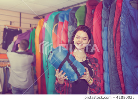 Cheerful female customer examining sleeping bags 41880023