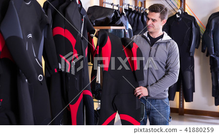 man is choosing wetsuit for diving 41880259