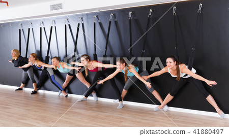 Girls practicing wall yoga with straps in studio 41880497
