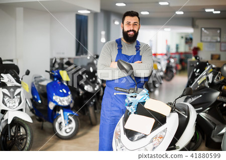 Man worker demonstrating motorbikes in workshop Man worker demonstrating motorbikes in workshop 41880599