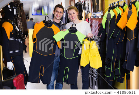 Man and woman are standing with modern diving costumes and flippers in the store. 41880611