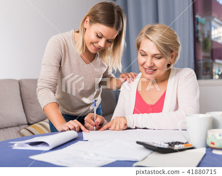Daughter helps mother to lead home accounting Daughter helps mother to lead home accounting 41880715