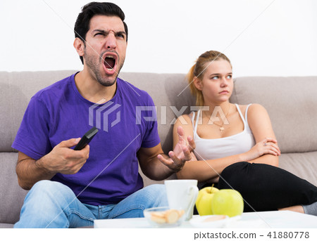 Man watching tv ignoring frustrated girl Man watching tv ignoring frustrated girl 41880778