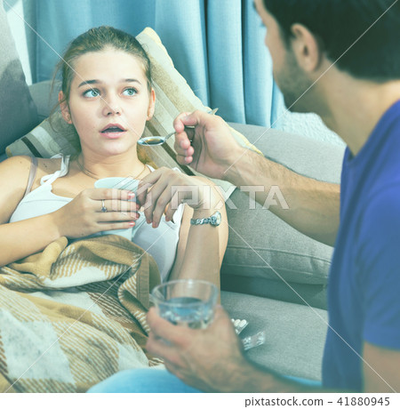 Loving man offering medicine to sick girl Loving man offering medicine to sick girl 41880945