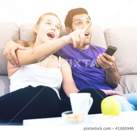 Cheerful couple on couch watching TV Cheerful couple on couch watching TV 41880946