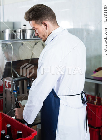 Careful man worker using machine to bottle wine Careful man worker using machine to bottle wine 41881187