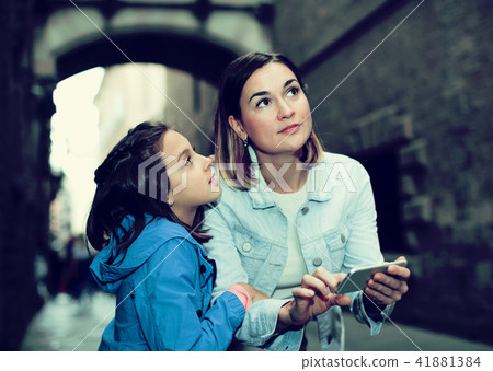Mother and daughter consulting guide in phone Mother and daughter consulting guide in phone 41881384