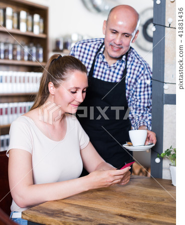 The waiter brought coffee to a young girl 41881436