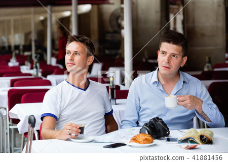 Couple of male tourists talking and drinking coffee Couple of male tourists talking and drinking coffee 41881456