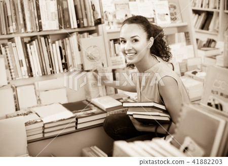Young cheerful woman student choosing books 41882203
