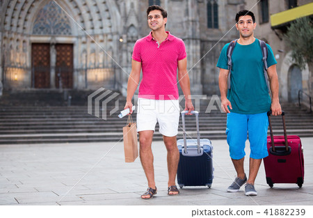 Men tourists are walking with suitcases in unknown city. 41882239
