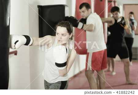 Young athlete female is beating a boxing bag Young athlete female is beating a boxing bag 41882242