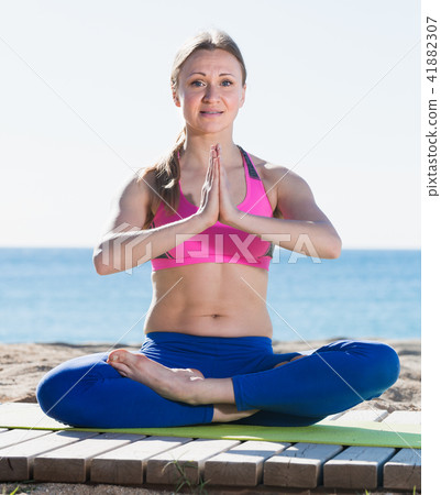 Positive woman training yoga asanas on the sand Positive woman training yoga asanas on the sand 41882307