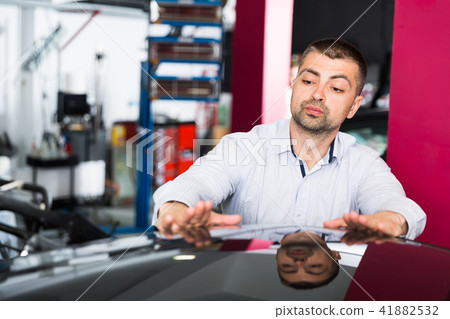 Male client inspecting painting quality of vehicle 41882532