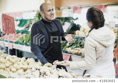 Mature man selling ginger to female customer Mature man selling ginger to female customer 41882681