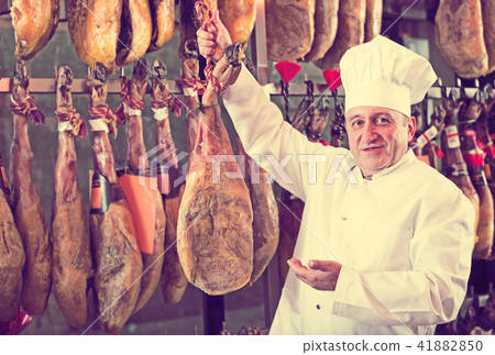 Smiling elderly man in uniform holding tasty jamon 41882850