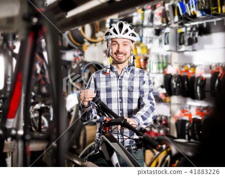 Man in helmet chooses convenient bike Man in helmet chooses convenient bike 41883226