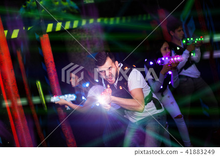 Emotional guy playing laser tag in colorful beams Emotional guy playing laser tag in colorful beams 41883249