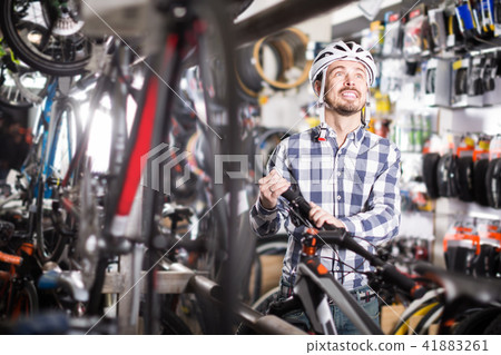 satisfied man in helmet chooses for himself sports bike in bicycle shop satisfied man in helmet chooses for himself sports bike in bicycle shop 41883261