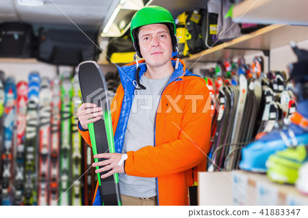 Customer man in ski equipment showing ski in store Customer man in ski equipment showing ski in store 41883347