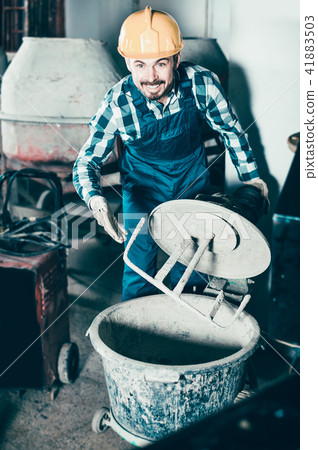 Smiling man using concrete mixer for construction work 41883503