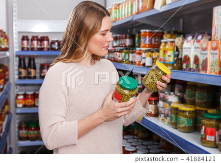 Positive female customer choosing pickle goods in store 41884121