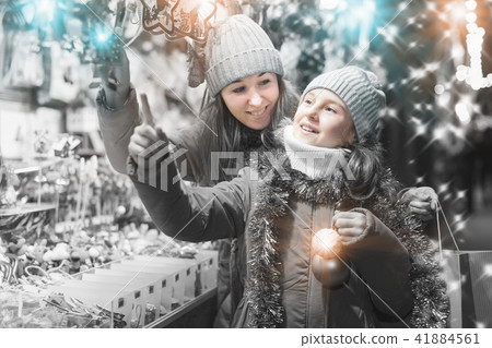 Young girl and her mother are choosing Christmas decorations Young girl and her mother are choosing Christmas decorations 41884561