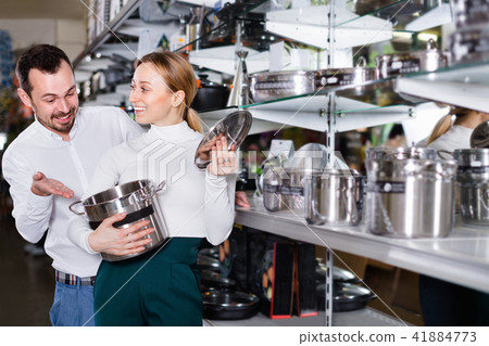 Young couple choosing new saucepan in dinnerware store Young couple choosing new saucepan in dinnerware store 41884773