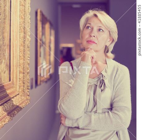 Mature woman in art museum near the painting Mature woman in art museum near the painting 41885455