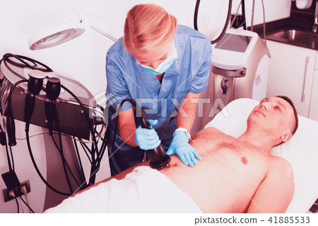 Woman doctor is doing vacuum massage procedure on belly of adult Woman doctor is doing vacuum massage procedure on belly of adult 41885533