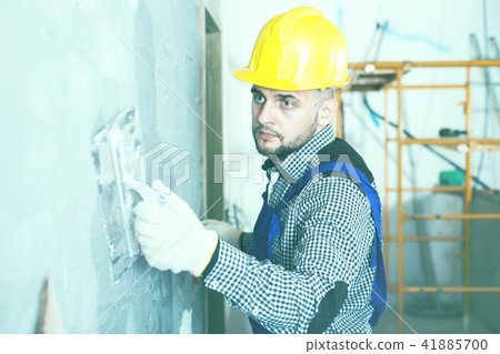 Professional in the helmet is plastering the wall 41885700