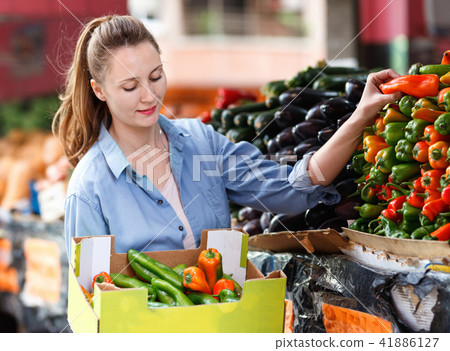 Woman is choosing vagetables with box in the market. 41886127