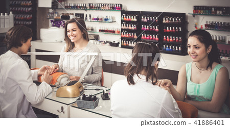 pair of smiling women clients getting manicure in nail salon 41886401