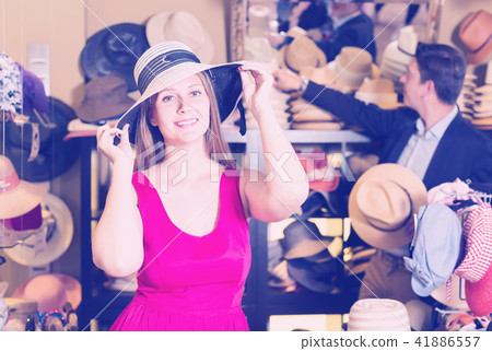 joyous young female and man choosing hats in the store 41886557