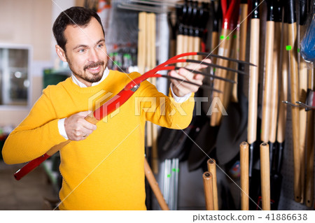 Male customer examining pitchforks 41886638
