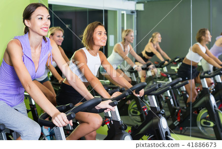 Girls during workout on stationary bicycle in fitness gym 41886673