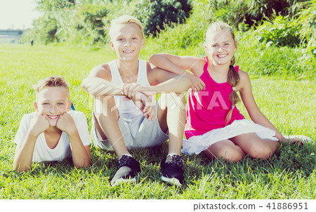 Girl with two friends resting on grass 41886951