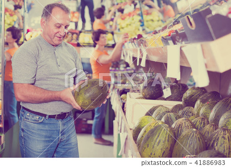 Glad man is choosing ripe melon in the store 41886983