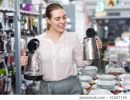 Woman housewife looking electric kettle in kitchen appliances section 41887146