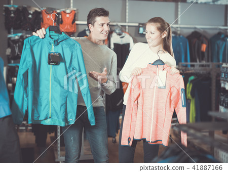 Cheerful couple in sports shop to choose sport clothes Cheerful couple in sports shop to choose sport clothes 41887166