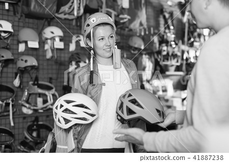 Smiling girl choosing helmet at sports store 41887238