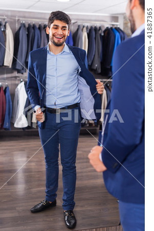 Adult man is trying on jacket in front of the mirror Adult man is trying on jacket in front of the mirror 41887365