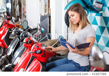 Smiling female is shopping and choosing new motobike in moto store. Smiling female is shopping and choosing new motobike in moto store. 41887366