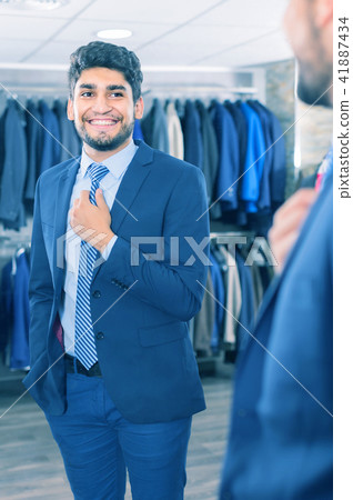 Smiling guy is trying on tie in front of the mirror Smiling guy is trying on tie in front of the mirror 41887434