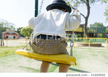 A kindergarten child playing with a swing in a par 41889092